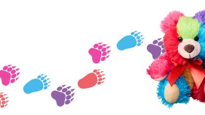 Bunter Teddybär mit gemalten, bunten Tatzen im Hintergrund