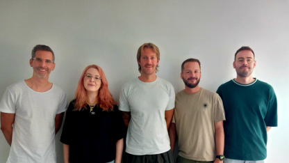 Fünf Personen stehen vor einer Wand und lächeln