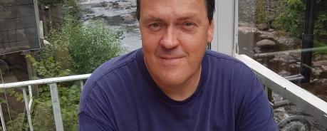 Mark Hayward Person vor Fluss und Häusern
