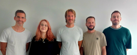 QuJu Team 2025 Fünf Personen stehen vor einer Wand und lächeln