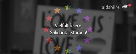 Sommerkundgebung_AHF Unscharfer Hintergrund; Sternenkreis in Regenbogenfarben, Schriftzug "Vielfalt feiern, Solidarität stärken"