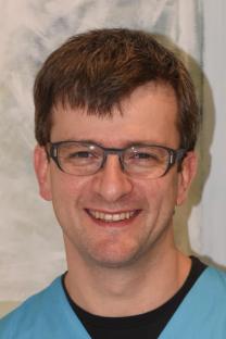 Person mit Brille und hellblauem Pullover